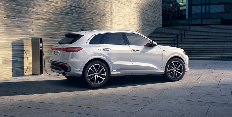 Ein Audi Q5 SUV e-hybrid l&auml;d an einer Wallbox