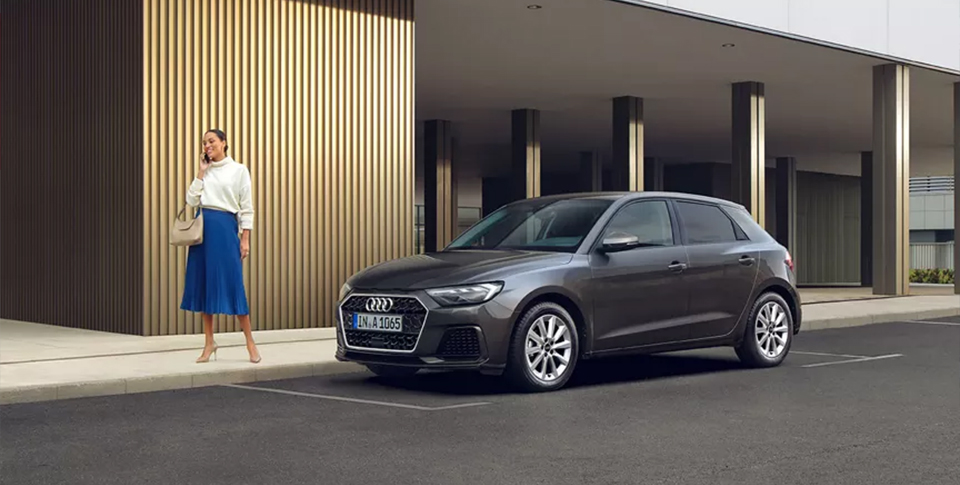 Ein Audi A1 der Parkt. Vor dem Fahrzeug steht eine Frau